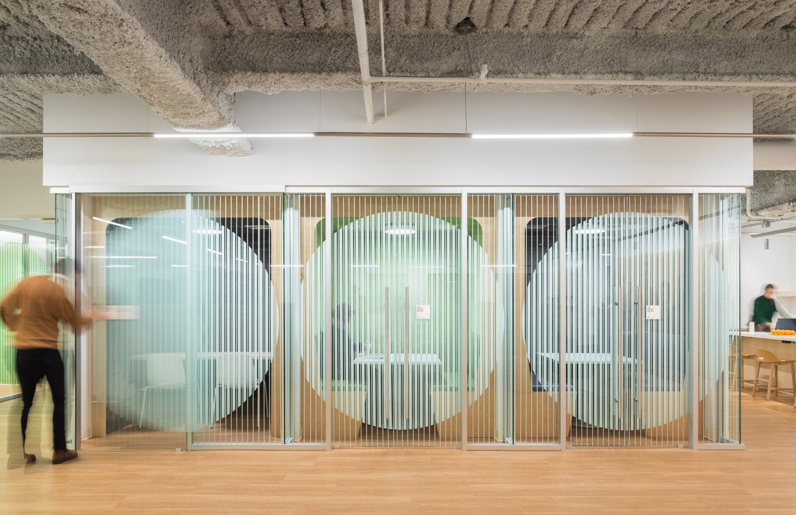 Glass-walled meeting rooms with frosted circle design for privacy.